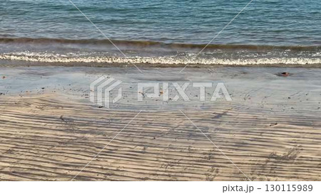 The tranquil beach is complemented by gentle waves that lap softly against the sand 130115989