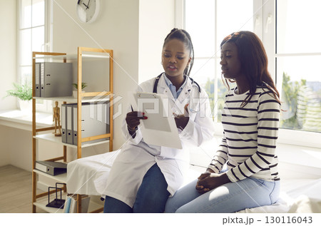 Doctor holding report file with appointment and prescribe treatment to a female patient in clinic. 130116043