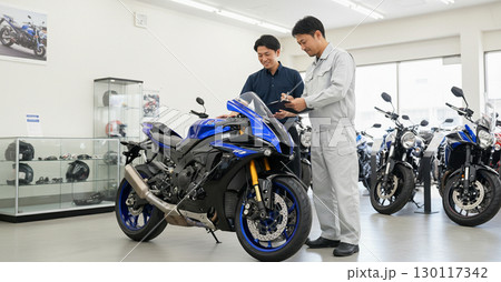 バイクショップで商談をする客と店員 130117342