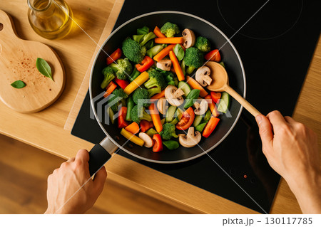 AI generated overhead view of fresh mixed vegetables being stir fried in a black pan with vibrant colors symbolizing healthy lifestyle freshness and simple home cooking 130117785