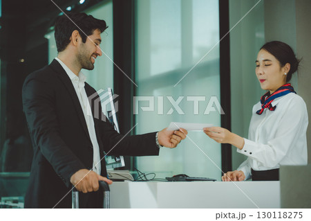 Business traveler receiving boarding pass from airline staff at airport check-in counter Business traveler receiving boarding pass from airline staff at airport check-in counter 130118275