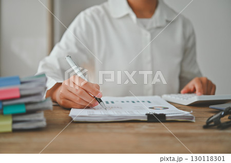 A woman is writing on a piece of paper with a pen A woman is writing on a piece of paper with a pen 130118301