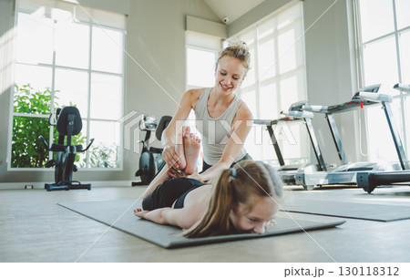 Mother Assisting Daughter in Deep Stretch Pose During Yoga Mother Assisting Daughter in Deep Stretch Pose During Yoga 130118312