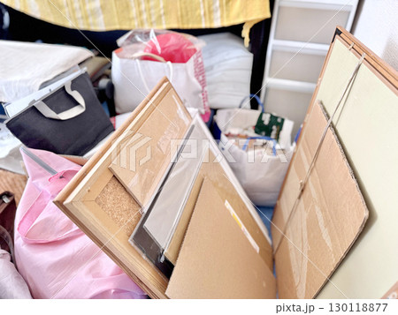 収納ケースの前の片付け中の複数の額縁や収納袋など 130118877