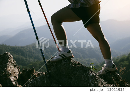 Hiking boot. Close up of female legs in boots on hiking trail on top of mountain outdoor. young woman reaching top of mountain. women feet wearing hiking boots on rock. Travel, vacation concept. 130119324