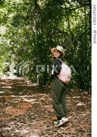 Young female traveler with backpack walking in national park or forest. recreation sport in nature. Female person bag, wave for hiking journey in woods. adventure in forest. trekking with backpack 130119583