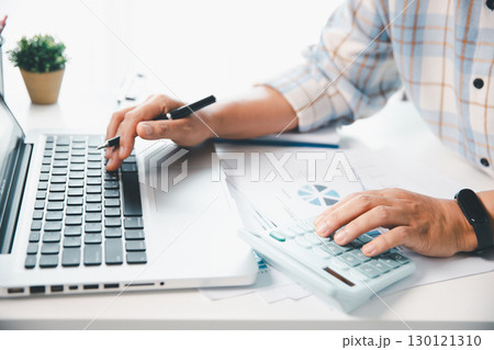 Accountant working on desk using calculator for calculate finance report in office. business finance, calculate tax by organizing financial documents, tracking income investment, accounting by hand. 130121310