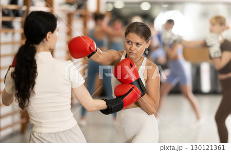 Women fight with hands, using all strength, courage during boxing lesson 130121361