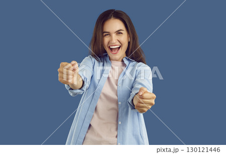 Cheerful brunette woman imagines she is driving and holding steering wheel on blue background. 130121446