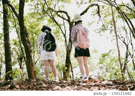 Two female friends with backpacks on vacation hiking through countryside together. Asian friend girls backpacker friend travel in forest wild together. happy and enjoying sunny day while hiking. 130121482