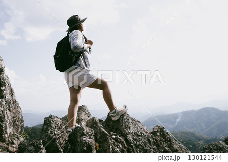 Woman hiker on top of mountain. Hiker with arms up on top of mountain successful young woman enjoying triumph. traveler exploring world. Hikers with backpacks relaxing. Sport and success concept. Woman hiker on top of mountain. Hiker with arms up on top of mountain successful young woman enjoying triumph. traveler exploring world. Hikers with backpacks relaxing. Sport and success concept. 130121544