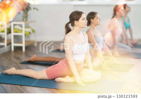 Young girl teaches yoga lesson, shows students technique of performing kapotasana asana Young girl teaches yoga lesson, shows students technique of performing kapotasana asana 130121593