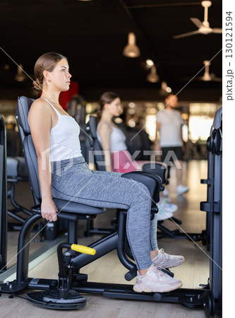 Young woman training her leg muscles on machine 130121594