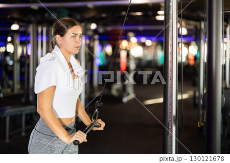 Slender athletic woman work out muscles of hands on cable crossover machine in fitness club Slender athletic woman work out muscles of hands on cable crossover machine in fitness club 130121678