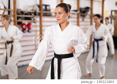 Young woman practicing kata standing in row with others 130121803