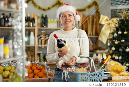 Smiling girl buying bottles of wine at grocery supermarket to celebrate Christmas 130121810
