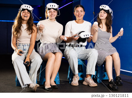 Cheerful teenage girls sitting in virtual reality game room 130121811