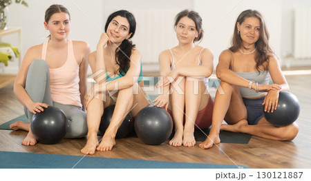 Happy portrait of young women posing with mats, going to practicing yoga at gym Happy portrait of young women posing with mats, going to practicing yoga at gym 130121887