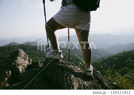 Hiking boot. Close up of female legs in boots on hiking trail on top of mountain outdoor. young woman reaching top of mountain. women feet wearing hiking boots on rock. Travel, vacation concept. 130121912
