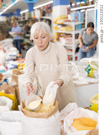 Old woman purchaser buying sugar sand in big supermarket 130122012