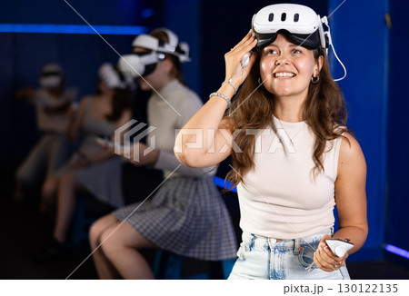 Excited young woman with VR glasses and controllers in gaming room Excited young woman with VR glasses and controllers in gaming room 130122135