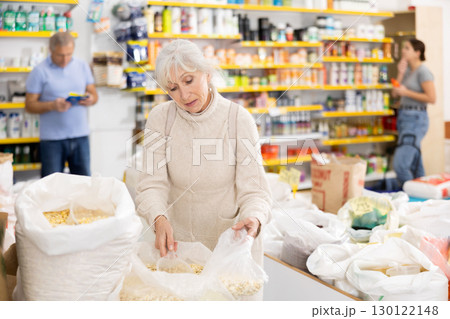 Elderly woman buying dried corn in grocery store 130122148