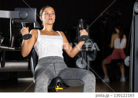 Young woman training her arms on machine Young woman training her arms on machine 130122165