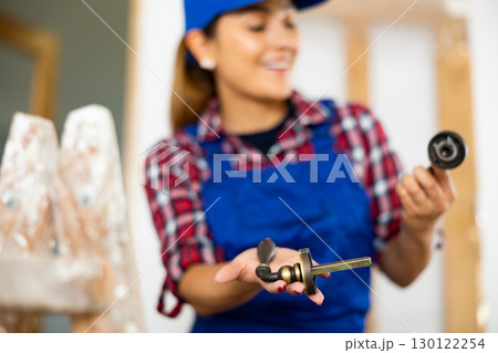 Defocused woman worker assembling door handle 130122254