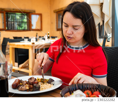 Woman enjoying her meal, eating parillada de carne 130122282