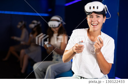 Excited young woman having fun in virtual reality room 130122433