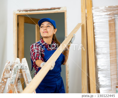 Cheerful female repairer carrying bunch of wooden planks Cheerful female repairer carrying bunch of wooden planks 130122445