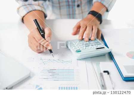 Accountant working on desk using calculator for calculate finance report in office. business finance, calculate tax by organizing financial documents, tracking income investment, accounting by hand. Accountant working on desk using calculator for calculate finance report in office. business finance, calculate tax by organizing financial documents, tracking income investment, accounting by hand. 130122470