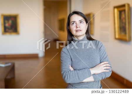 Female art lover viewing collection of paintings in art museum 130122489