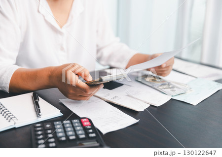 Using calculating machine, household carefully manages each bill and expense to plan financial budget, ensuring timely payment, consistent saving, smart investment for secure home finance strategy. Using calculating machine, household carefully manages each bill and expense to plan financial budget, ensuring timely payment, consistent saving, smart investment for secure home finance strategy. 130122647