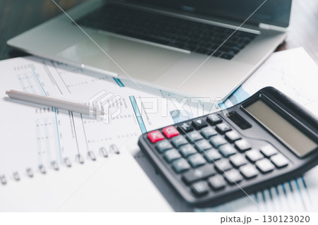 Auditor reviews financial statement and balance sheet on desk using a calculator, representing the concept of accounting, audit, and finance in preparing a detailed financial report for the business. 130123020