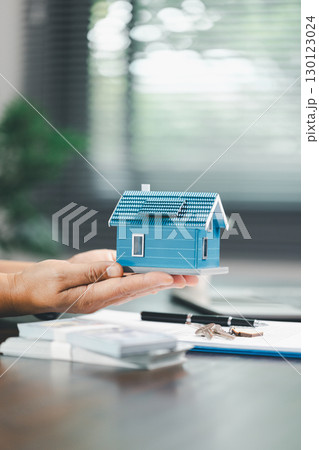 House model placed beside money coins illustrates concept of saving and financial planning for buying home, highlighting investment, mortgage options, home loans, refinancing, smart finance strategies 130123024