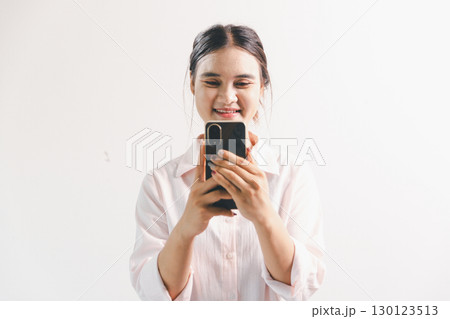 Asian woman rejoicing, looking happy, champion, fist pump gesture, standing over white background. young woman had happy, positive expression on her face, highlighted by bright smile. 130123513