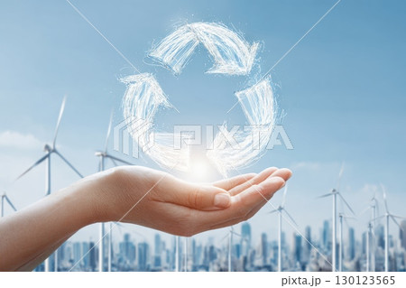 Hands Holding Glowing Circular Economy Icon Over Wind Turbines and City Skyline Hands Holding Glowing Circular Economy Icon Over Wind Turbines and City Skyline 130123565