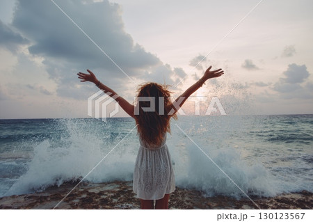 A woman with long hair is standing on a beach 130123567