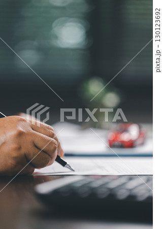 Client is signing the contract and insurance document for the purchase of a vehicle, finalizing finance and loan agreements that mark the approval of a smart investment and successful car deal. Client is signing the contract and insurance document for the purchase of a vehicle, finalizing finance and loan agreements that mark the approval of a smart investment and successful car deal. 130123692