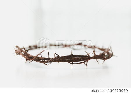 Crown of thorns on white table background. Easter, central celebration in Christianity, honors sacrifice of Jesus Christ, crown of thorns symbolizes redemption, faith, deep spirituality of religion. 130123959