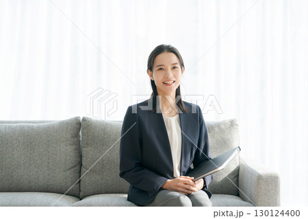 ソファに座るスーツ姿の女性 ソファに座るスーツ姿の女性 130124400