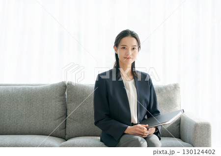 ソファに座るスーツ姿の女性 ソファに座るスーツ姿の女性 130124402