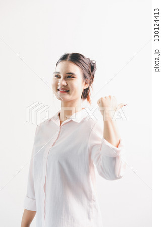 Asian woman rejoicing, looking happy, champion, fist pump gesture, standing over white background. young woman had happy, positive expression on her face, highlighted by bright smile. 130124413