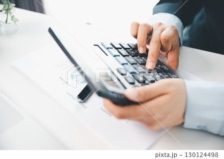 Accountant working on desk using calculator for calculate finance report in office. business finance, calculate tax by organizing financial documents, tracking income investment, accounting by hand. Accountant working on desk using calculator for calculate finance report in office. business finance, calculate tax by organizing financial documents, tracking income investment, accounting by hand. 130124498