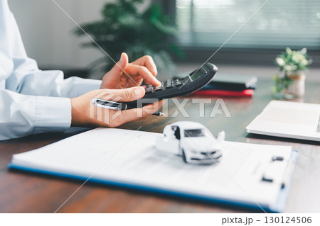 Dealership service desk, professional car salesman assists client with sale, finance documents for vehicle, ensuring smooth business transaction in retail transportation sector through signed contract 130124506