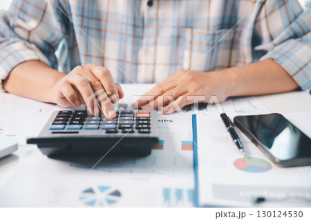 Accountant working on desk using calculator for calculate finance report in office. business finance, calculate tax by organizing financial documents, tracking income investment, accounting by hand. Accountant working on desk using calculator for calculate finance report in office. business finance, calculate tax by organizing financial documents, tracking income investment, accounting by hand. 130124530