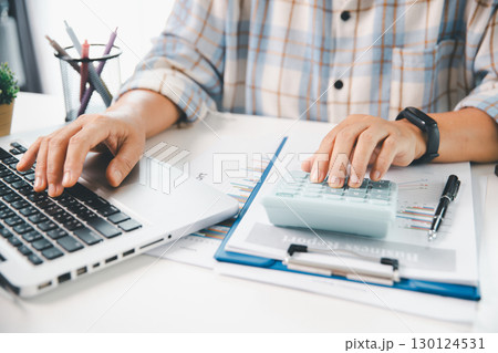 Accountant working on desk using calculator for calculate finance report in office. business finance, calculate tax by organizing financial documents, tracking income investment, accounting by hand. Accountant working on desk using calculator for calculate finance report in office. business finance, calculate tax by organizing financial documents, tracking income investment, accounting by hand. 130124531