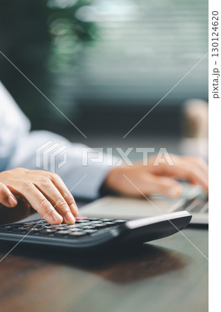 Businesswoman at table, calculator, monthly tax calculations, budgeting, managing expenses-illustrating business, finance, accounting, banking concept essential for effective budget management. Businesswoman at table, calculator, monthly tax calculations, budgeting, managing expenses-illustrating business, finance, accounting, banking concept essential for effective budget management. 130124620