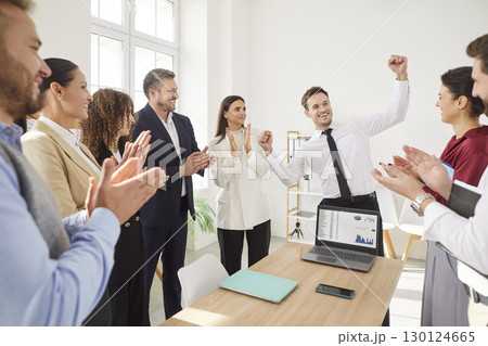 Happy business team celebrating success in work with manager raising fists and colleagues applauding Happy business team celebrating success in work with manager raising fists and colleagues applauding 130124665